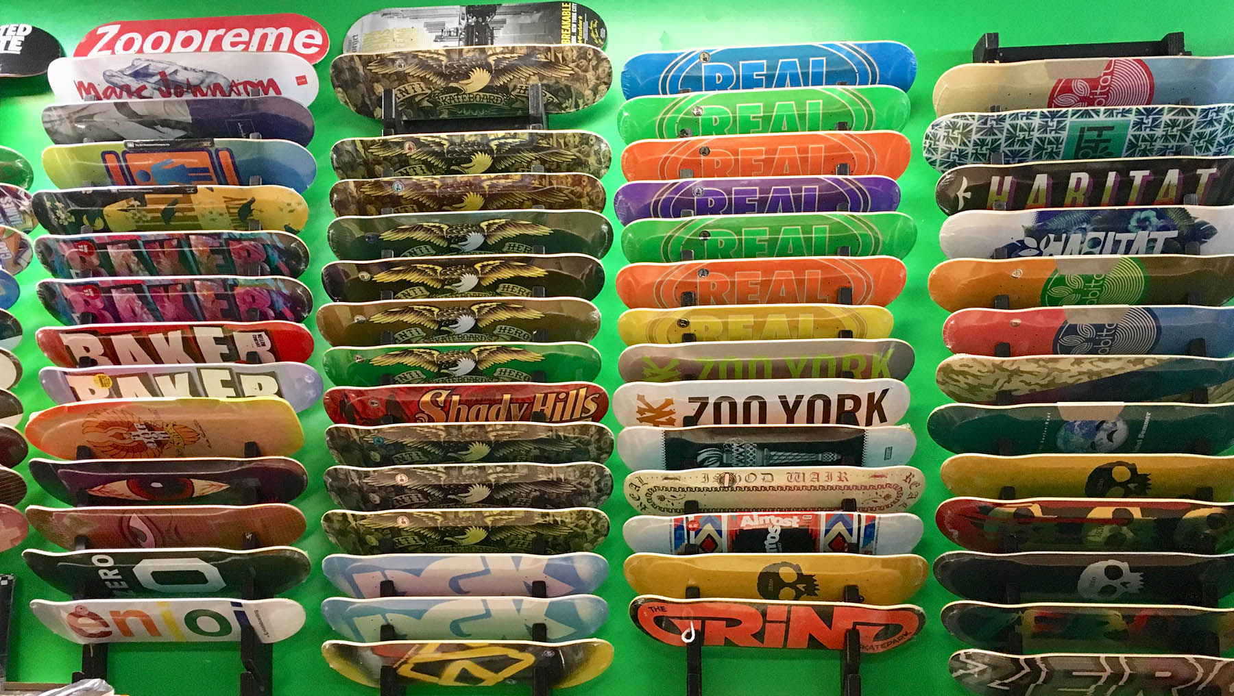 Collection of variously designed skateboard decks on a green wall.